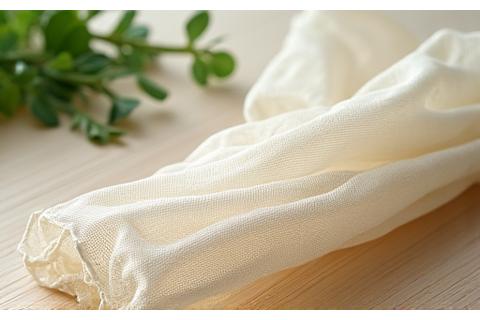 Finely meshed, off-white plant-based fishing net draped over a wooden surface, showing its flexible and durable texture.