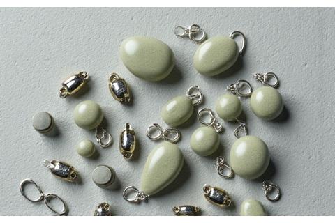 Assortment of small, dull metallic-looking biodegradable weights, swivels, and clips laid out on a clean stone background.