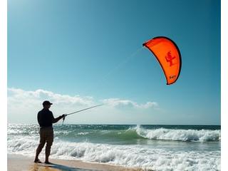 Kite fishing on a sandy beach with the kite far out over the waves.